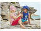 Deux enfants, une fille avec un chapeau rose et un garçon avec une casquette bleue, jouent sur la plage.