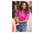 Femme souriante en t-shirt rose et short en jean, achetant des fruits.