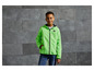 Un garçon porte une veste verte à capuche avec un logo.