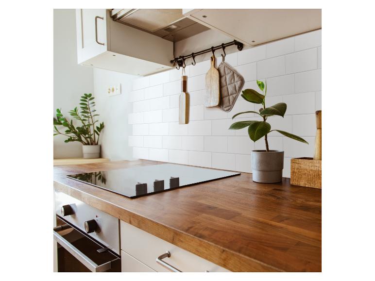Cuisine moderne avec une plaque à induction noire, des comptoirs en bois et des carreaux blancs.