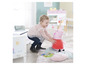 Une petite fille joue avec une peluche Peppa Pig et une couverture.