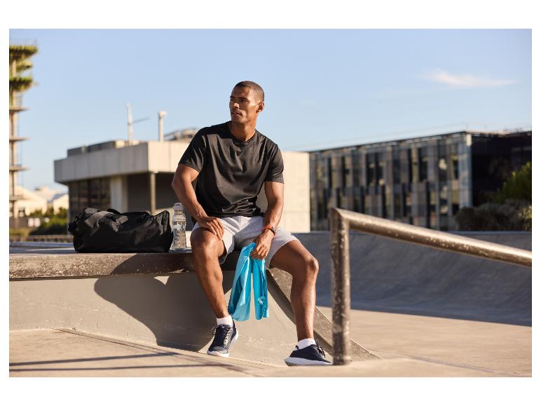 Homme reposant après l'entraînement, avec sac de sport, serviette et bouteille d'eau.