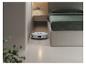 Robot aspirateur nettoyant le sol d'une chambre avec un lit et une table de chevet.