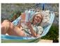 Femme se relaxant dans un hamac avec un livre dans un jardin.