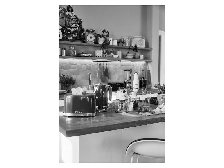 Grille-pain, bouilloire et autres appareils de cuisine style 1973 sur un comptoir en bois.