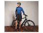 Un homme avec un casque et des chaussures de vélo est à côté d'un vélo noir.