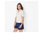 Femme en polo blanc côtelé à rayures et short bleu foncé.