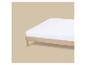 Matelas blanc sur un cadre de lit en bois clair sur fond beige.