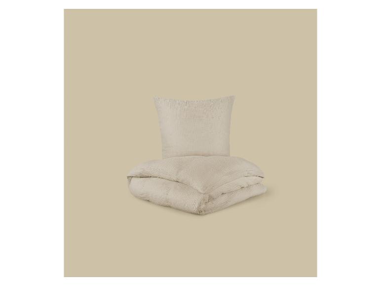 Parure de lit beige avec housse de couette et taie d'oreiller sur fond assorti.