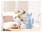 Un lapin bleu avec les oreilles dressées sur une table en bois avec une tasse de thé et un vase.