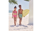 Deux enfants sur la plage en maillots de bain avec une planche de surf.