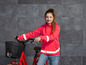 Une fille avec une veste rouge et un vélo avec un panier.