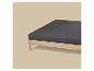 Lit avec cadre en bois et drap-housse gris foncé sur fond beige.