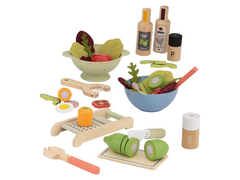 Ensemble de salade jouet en bois avec bols, légumes, râpe, éplucheur et bouteilles d'assaisonnement.