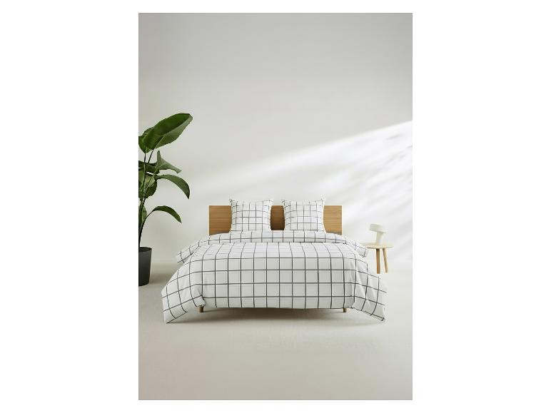 Lit avec parure de lit à carreaux blancs et noirs, tête de lit en bois et plante verte