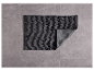 Tapis de bain gris foncé sur un sol carrelé.