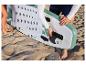 Une personne installe l'aileron sur un stand up paddle HOME DELUXE Moana vert menthe sur la plage.