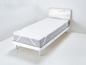 Un matelas blanc avec un protège-matelas gris sur un cadre de lit en bois.