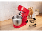 Robot pâtissier rouge avec fouet dans un bol de crème fouettée, sur un comptoir de cuisine.