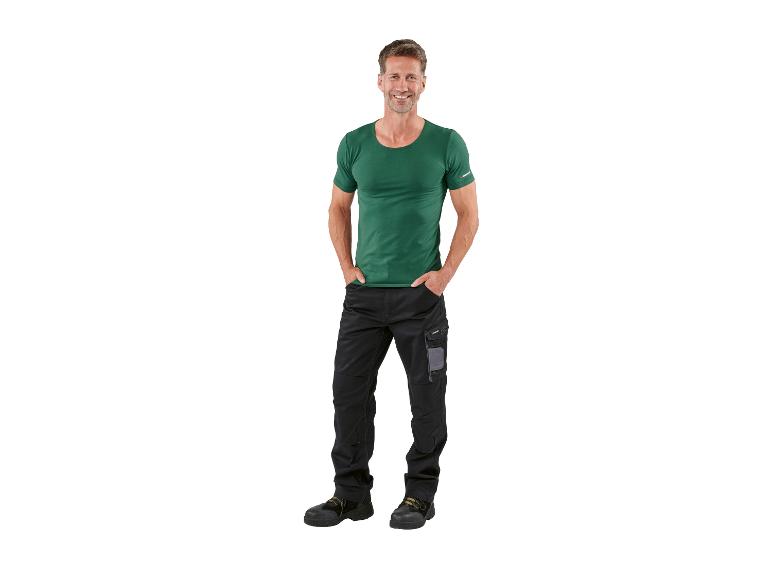 Homme souriant en t-shirt vert et pantalon de travail noir