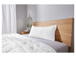 Une couette et un oreiller blancs sur un lit avec une tête de lit en bois.
