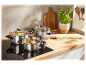 Trois casseroles en acier inoxydable avec couvercles en verre sur une plaque de cuisson à induction.