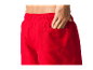Un homme avec une main dans la poche de son short rouge.
