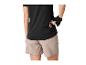 Femme en haut de sport noir et short beige mettant une barre de collation dans une poche arrière.