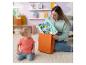 Une femme sort des jouets pour bébé en forme de personnages d'un sac cadeau orange, un bébé la regarde.