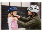 Un homme aide un enfant à mettre un casque de vélo Craftig bleu et blanc.