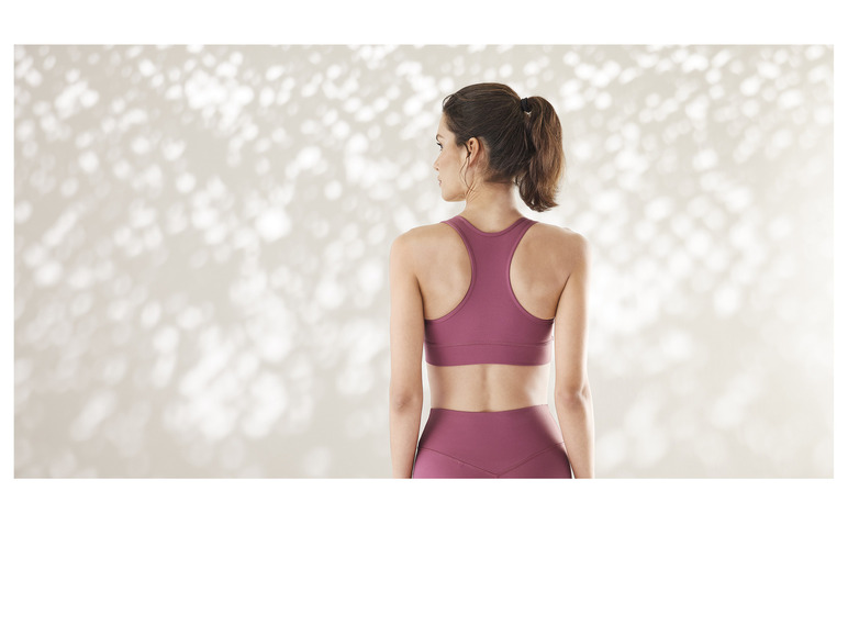 Une femme porte un soutien-gorge de sport rose et des leggings.