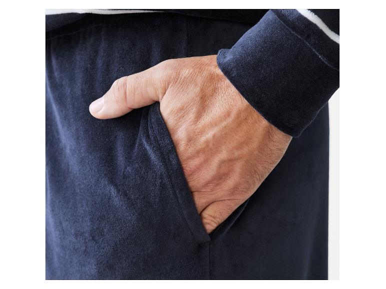 Un homme porte un pantalon bleu marine avec des rayures blanches.