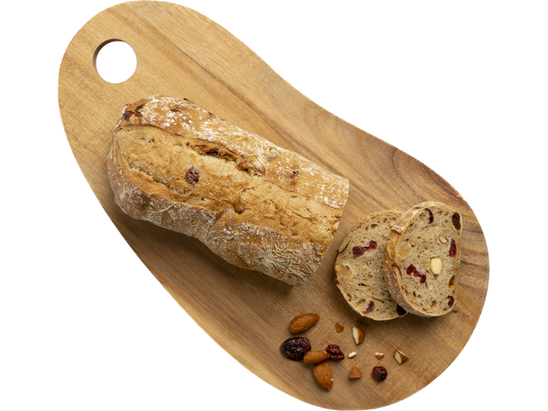 Pain aux canneberges et amandes sur une planche à découper en bois.