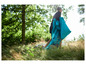Une personne marche dans de hautes herbes avec un sac de couchage bleu.