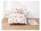 Un lit avec des draps à fleurs roses et deux oreillers.