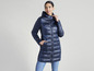 Une femme porte une veste matelassée bleu marine avec capuche.