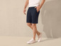 Un homme porte un short chino bleu et des baskets blanches.