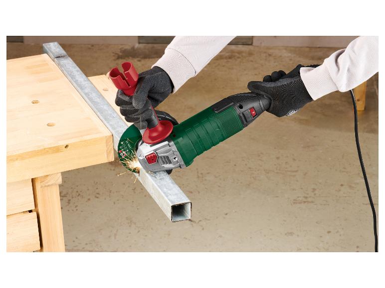 Personne coupant du métal avec une meuleuse d'angle, étincelles, sur un établi en bois.