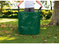 Personne dans le jardin avec un sac vert de déchets de jardin rempli de feuilles.