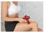 Une femme en tenue de sport utilise un pistolet de massage rouge sur sa jambe.