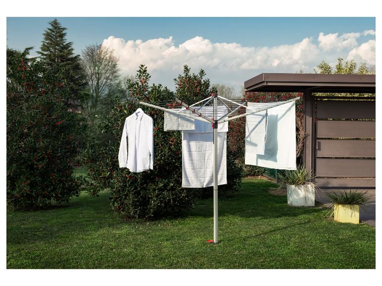 Chemise blanche et serviettes séchant sur un étendoir rotatif extérieur dans un jardin.