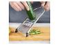 Mains coupant du concombre avec une mandoline Genius sur une planche à découper en bois