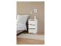 Une table de chevet blanche à trois tiroirs dans une chambre à coucher.