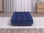 Un matelas pneumatique bleu sur un tapis blanc