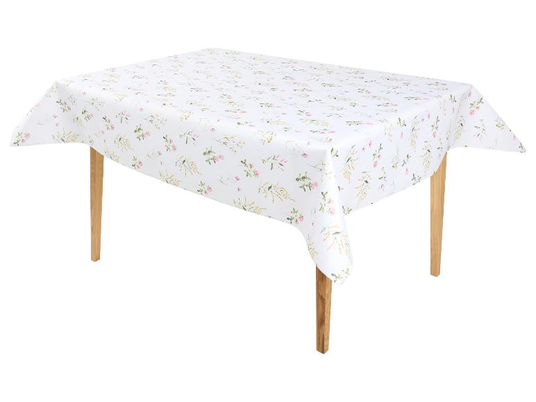 Nappe blanche à motifs de fleurs roses et jaunes sur une table en bois.
