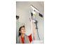 Femme nettoyant la vitre de la cabine de douche avec un nettoyeur de vitres.