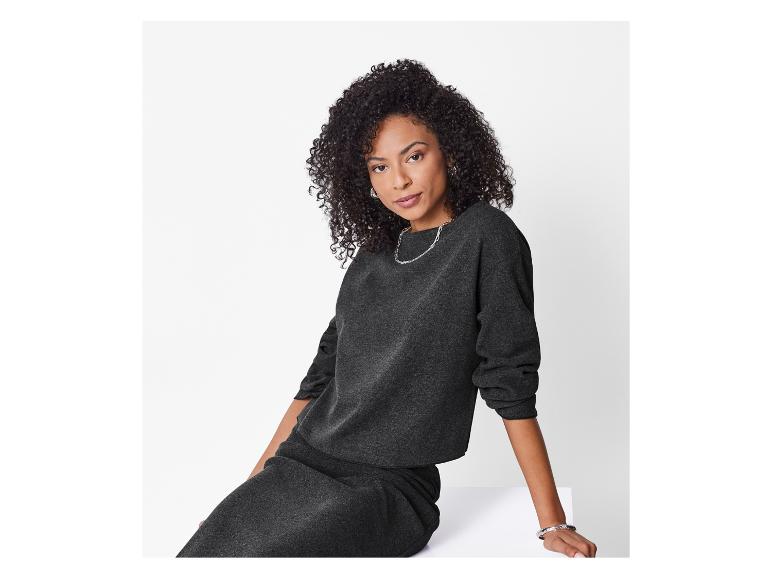 Femme en sweat-shirt gris foncé et jupe assortie avec des bijoux en argent.