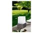 Une lampe blanche carrée avec un piétement en rotin sur une terrasse en bois.