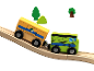 Train jouet en bois avec deux wagons sur une voie montante, avec des arbres en arrière-plan.