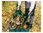 Personne ramassant des feuilles d'automne dans un sac de jardin vert avec des ramasse-feuilles.